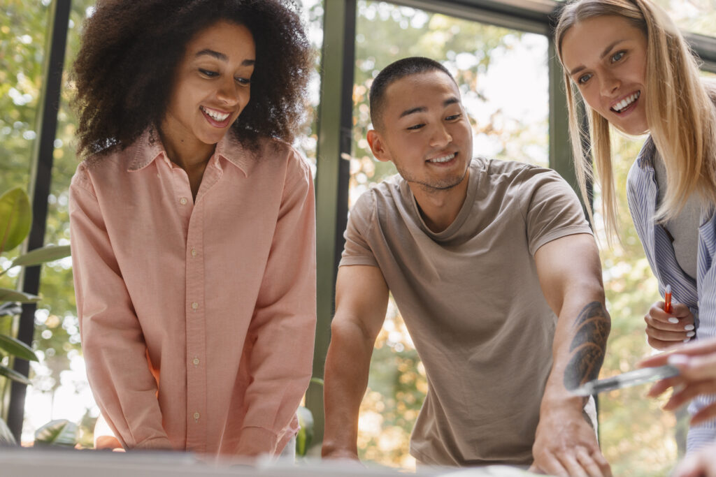 7 motivos para criar um CoE em tecnologia 1 Uma equipe de três pessoas sorridentes compõe um time de CoE.