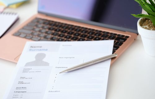 Ballpoint pen lying on resume document for employment near laptop closeup. Job search online concept