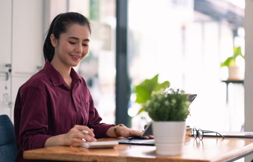 Charming asian female accountant or banker making calculations. Savings, finances and economy concept through a digital tablet.