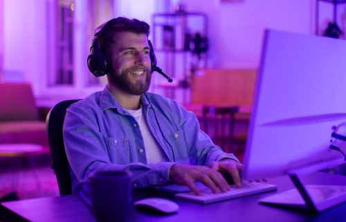 With intense concentration, this millennial guy epitomizes a gamer deeply invested in his match, reflecting the addiction and engagement of home gaming