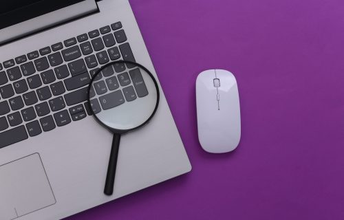 Search information. Laptop with pc mouse, magnifier on purple background. Top view