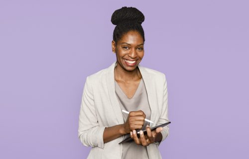 Smiling woman writing notes on tablet digital device