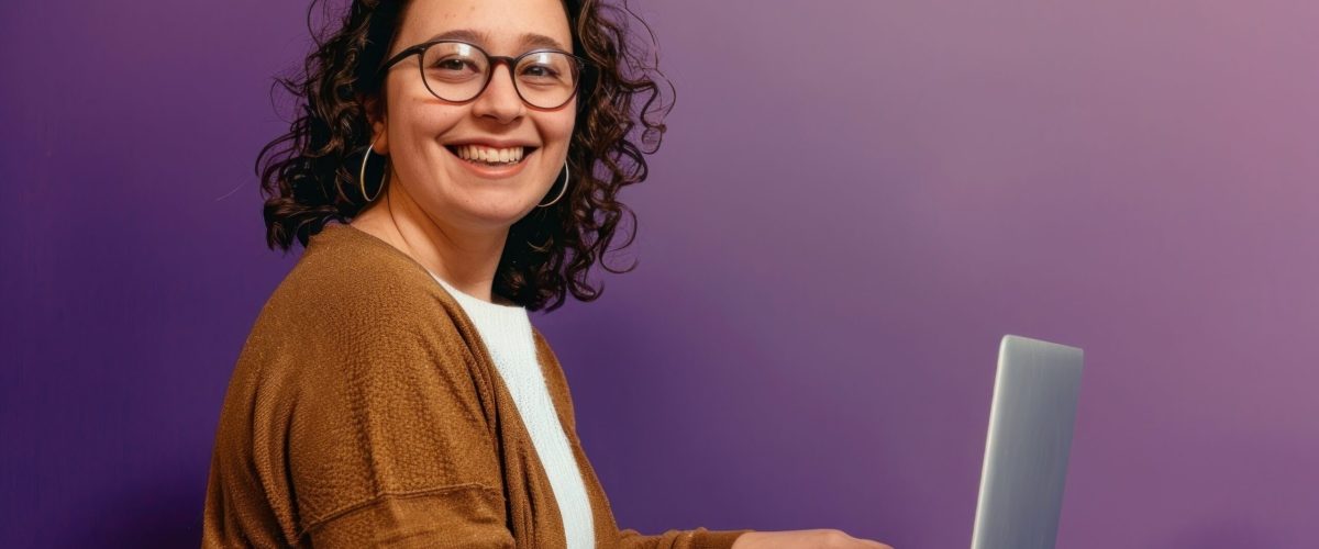 Woman wearing glasses smile to a camera with a laptop background happy electronics.